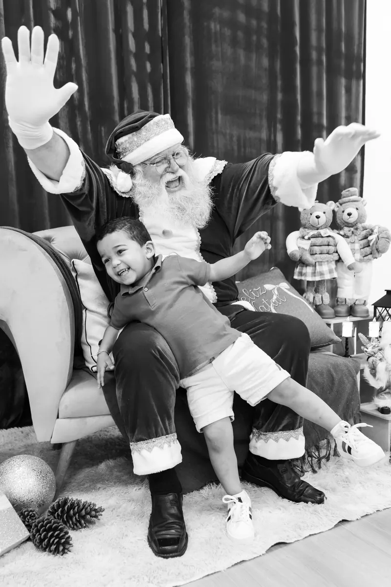 Menino e Papai Noel acenando, em preto e branco